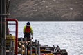 Back shot of a fisherman on dock in safety gear clothes holding fishing rod Royalty Free Stock Photo