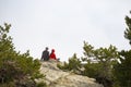 Back shot of male and female hikers sitting on a cliff edge.
