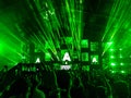 Back shot of people and Armin Van Buuren playing on stage with green neon lights