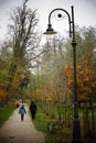 Back shot of People walking on a footpath of a park on a cloudy day in the autumn