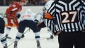 Back shot of referee on a hockey match. Ref looking at face off scene before throw-in. Very intense moment in