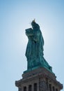 Back shot from statue of liberty with sun behind the statue and glowing edges. Torch, Pedestal and blue sky visible Royalty Free Stock Photo