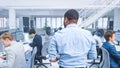 Back Shot of a Young Manager Walking Pass His Business Colleagues and Supervise Their Work. Diverse Royalty Free Stock Photo