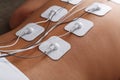 Muscle stimulator with electrodes, bacBack and shoulder massage with a muscle stimulator with attached electrodes along Royalty Free Stock Photo