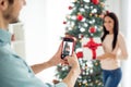 Back side blurred photo of two people man making photo on his cell phone of wife hold package gift for christmas time x Royalty Free Stock Photo