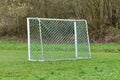 Back side of empty soccer goal with white frame and green net standing on grass Royalty Free Stock Photo