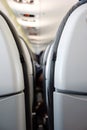 Back side of generic airplane seats next to each other shallow depth of field view forward to passengers