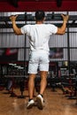 Back side of a gym athlete wearing a white blank shirt doing a pull up at a gym Royalty Free Stock Photo
