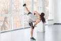 Back side of healthy muscular young adult man with curly long hair is posing on professional karate position with raised legs,