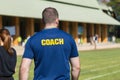 Back side of a male athlete coach in deep blue t-shirt with yell