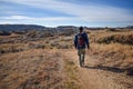 The back side of a man hiking a dirt path