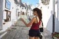 Back side of traveler girl searching right direction on map. Young woman visit Alberobello trulli in Apulia region, Italy Royalty Free Stock Photo