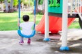 Back side view of Asian toddler boy is sitting on a swing gently. Peace of mind on a winter afternoon. Royalty Free Stock Photo