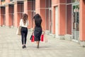 Back side view of two girls walking near shopping center after day of purchases Royalty Free Stock Photo