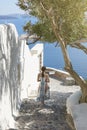 Back side of woman tourist walking on stairs in Oia village, Santorini with the mediterranean sea. Santorini Europe summer