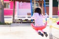 Back side young Asian girl in morning playing swing on playground after waking up. Royalty Free Stock Photo