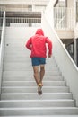 Back of sport man in red hood running up at steps, motion blur.. Royalty Free Stock Photo