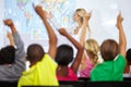 Back of students, teacher and raise hands for questions, education or learning with geography quiz in classroom. Youth Royalty Free Stock Photo