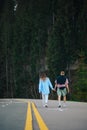 Back of a stylish couple on a walk in the woods on an asphalt road. Man and woman spend time together in nature in the mountains. Royalty Free Stock Photo