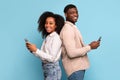 Back-to-back african american couple with phones on blue background