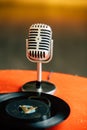 Back to 50s - nostalgic image of a 50`s microphone standing on an old orange table with old vinyl records