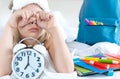 Back to school. Alarm,clock. Little girl, schoolgirl sleeps in bed,wakes up early to study,rubs eyes.Backpack,multi colored Royalty Free Stock Photo