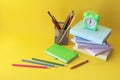 Back to school, alarm clock, stack of books and pencils on bright background Royalty Free Stock Photo