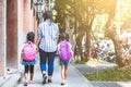 Asian mother and daughter pupil girl with backpack holding hand and going to school together