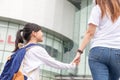 Back to school. Asian mother and daughter pupil girl with backpack holding hand and going to school together. Beginning of lessons