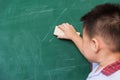 Child boy kindergarten in student uniform wiping clean or erase chalk on green school blackboard Royalty Free Stock Photo