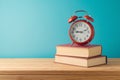 Back to school background with books and alarm clock on wooden table over blue background Royalty Free Stock Photo