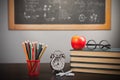 Back to school background with books, pencils and apple over chalkboard and wooden table Royalty Free Stock Photo