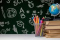 Back to school background with books, pencils and globe on white table on a green blackboard background Royalty Free Stock Photo