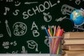 Back to school background with books, pencils and globe on white table on a green blackboard background Royalty Free Stock Photo