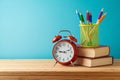 Back to school background with pencils, books and alarm clock on wooden table over blue background Royalty Free Stock Photo