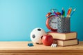 Back to school background with pencils, football ball, books, apple and alarm clock on wooden table over blue background Royalty Free Stock Photo