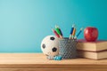 Back to school background with pencils, football ball, books and apple on wooden table over blue background Royalty Free Stock Photo