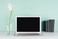 Back to school background - workplace with blank notebook monitor, black books and white fresh flowers in light green mint menthe. Royalty Free Stock Photo