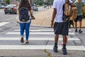 Back to school - the backs of college students crossing urban crosswalk with backpacks - ethnic diversity and casual dress with ca Royalty Free Stock Photo