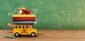 Back to school banner. Funny School bus with books and accessory in front of green chalkboard with copy space.