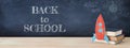 Back to school banner. Painted cardboard rocket next to books in front of classroom blackboard. Royalty Free Stock Photo