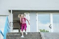 Back to school. Beautiful blond schoolgirl with red backpack running outside the primary school.