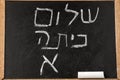 Back to School. Blackboard with Hello First Grade text in Hebrew written with white chalk.