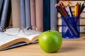 Back to school. Books, green apple, pencils and glasses on wooden table Royalty Free Stock Photo