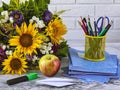 Back to school. A bouquet of autumn flowers, stationery, an apple, a stack of school notebooks