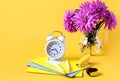 Back to school: a bouquet of pastel dahlias in a glass vase, a stack of school notebooks, school supplies, an alarm clock on a Royalty Free Stock Photo