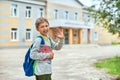 Back to school. A boy from an elementary school in the school yard waves Royalty Free Stock Photo