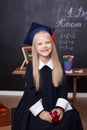 Back to school! Cheerful little girl at school on a black background. Looking into the camera. School concept. Schoolgirl in class