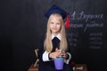 Back to school! Cheerful little girl at school on a black background. Looking into the camera. School concept. Schoolgirl in the c Royalty Free Stock Photo