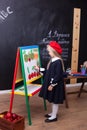 Back to school! Cheerful little girl is standing near the school board. School concept. Schoolgirl answers at lesson. The kid is s Royalty Free Stock Photo